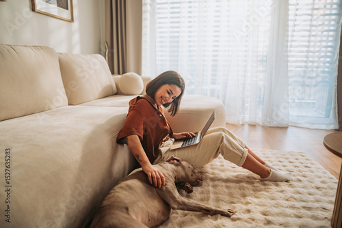 A woman works on her laptop at home, enjoying a cozy moment with her dog