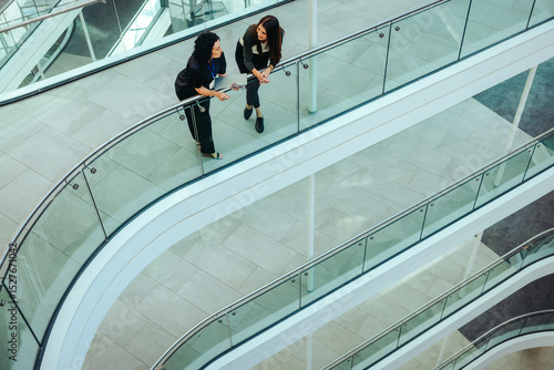 Fényképezés Two female coworkers conversing on a modern office flyover