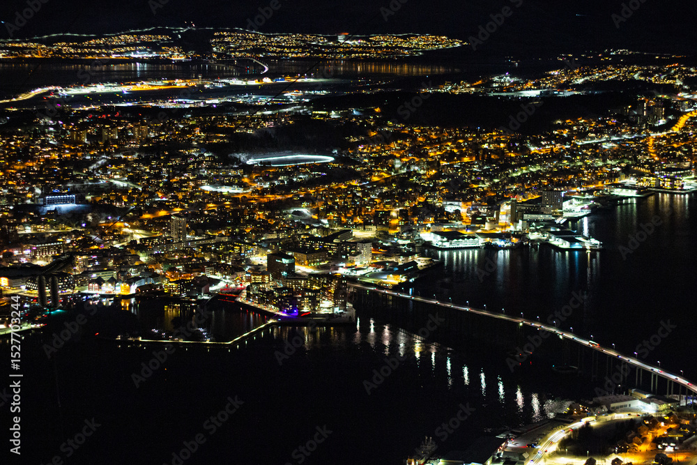 Naklejka premium View from Fjellheisen mountain at night on the Norwegian city of Tromso and the Tromso Bridge (Norwegian: Tromsobrua) connecting the mainland (Tromsdalen) and island (Tromsoya) parts of the city.