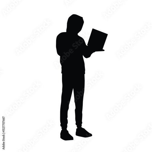 Silhouette of a hacker holding and using a laptop while standing
