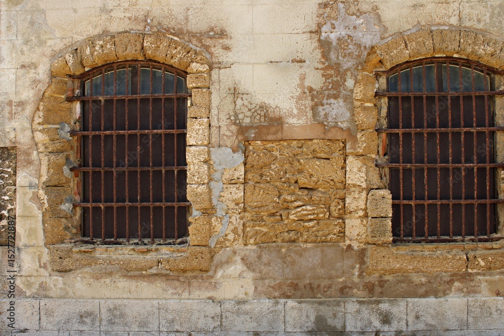 Obraz premium Old windows in Castle of San Sebastián in Cadiz, Andalusia. Spain. Coastal atmosphere that reflects centuries of maritime heritage and architectural decay