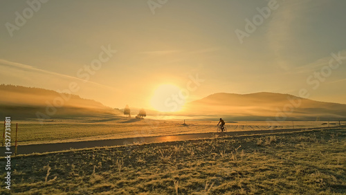 Foto Breathtaking aerial view of a person riding a bicycle through a serene countryside at sunset