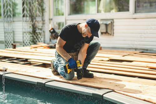 Fotografie Handyman worker making patio outside close to a pool installing floor