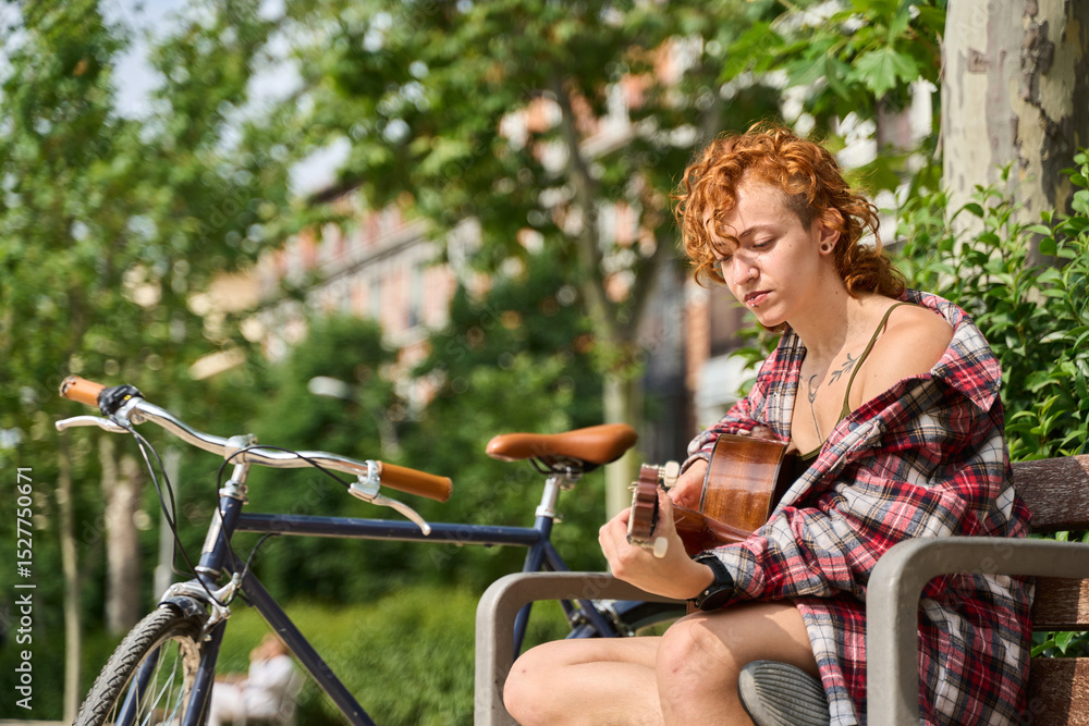 Obraz premium Young woman playing guitar in a city park