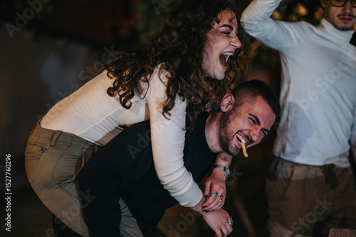 Billede på lærred A group of friends sharing spontaneous laughter and joy, showcasing carefree and happy interactions during a lively night out under ambient lighting