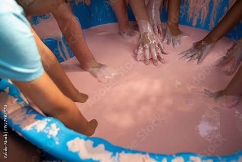 Science experiment with children dipping hands into oobleck, cornstarch and water mixture