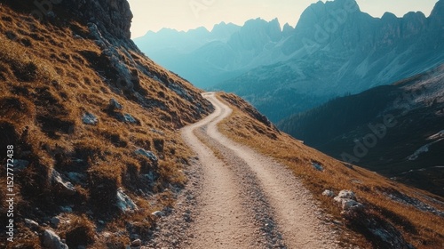 Narrow gravel trail hugging the mountainside in the Dolomites, clear skies and breathtaking panoramic views, no people