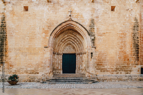 Gothic entrance of the Ciutadella de Menorca Cathedral are presented, featuring its iconic archway and historic stone. This prominent religious landmark is a part of Menorca cultural heritage