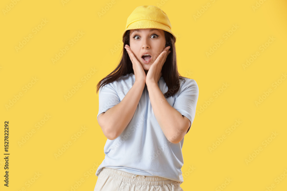 Surprised young woman in bucket hat on yellow background Surprised young woman in bucket hat on yellow background