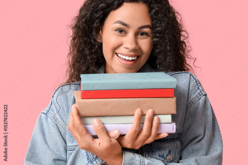 Happy young African-American woman with books on pink background Happy young African-American woman with books on pink background