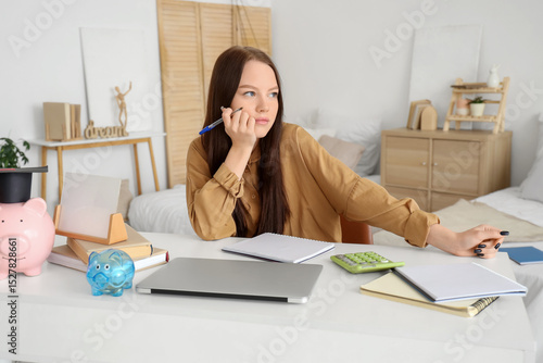 Young woman with savings for education planning her budget at home