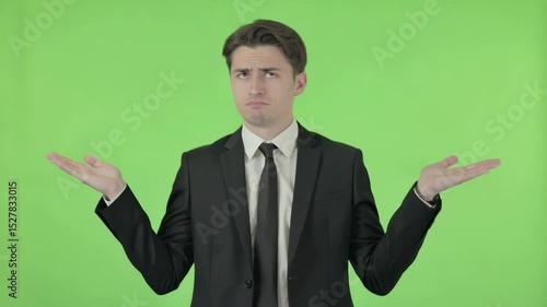 Businessman showing helplessness on green background.Young businessman shrugging shoulders on green screen background