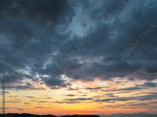 Beautiful cloudy red sunrise over sea with beach, waves and mountains in the background. Impressive structure texture in the sky
