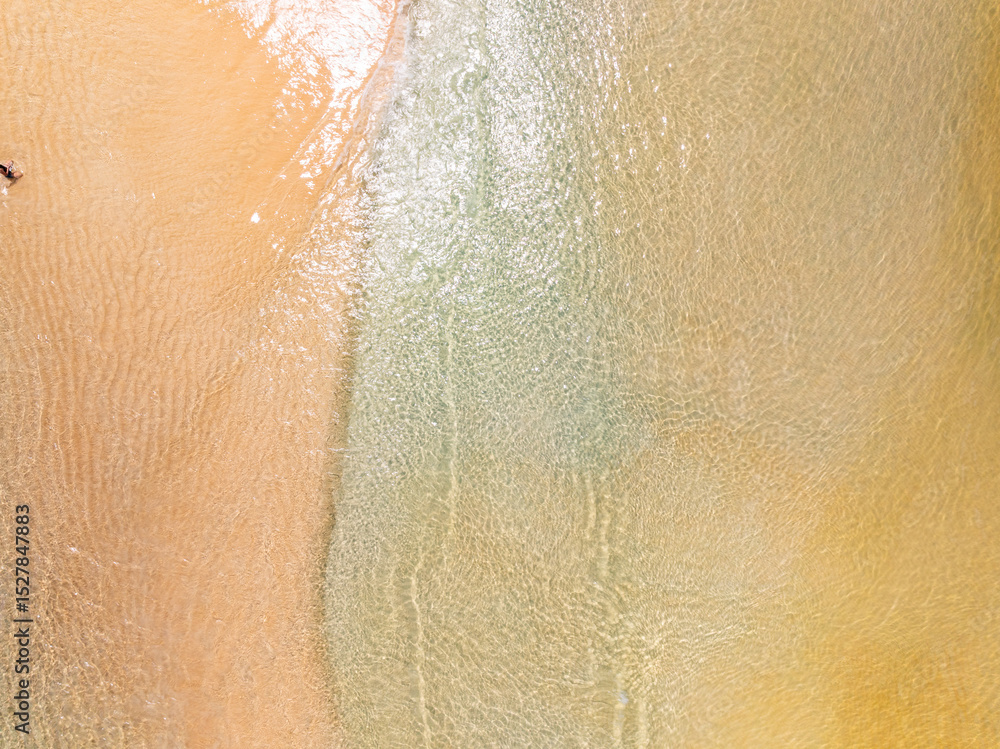 Fototapeta premium Top view beach with waves crashing on sandy shore,Beautiful waves sea surface in summer seascape background,Amazing beach colorful water background