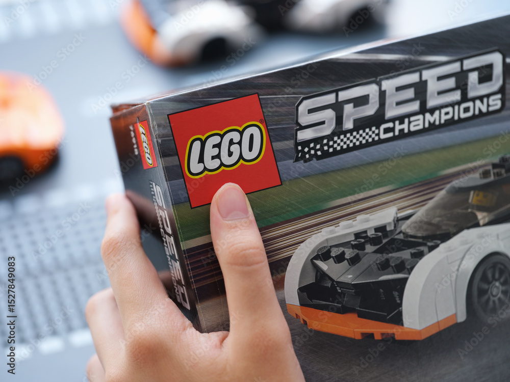 Obraz premium Tambov, Russian Federation - June 09, 2025 A young boy holding a Lego Speed Champions box in his hands near Lego cars.