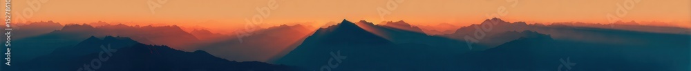 Obraz premium A panoramic view of mountains at sunrise, with the sun's rays piercing through them