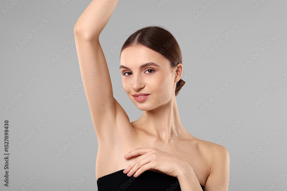 Fototapeta premium Young woman showing smooth skin after epilation on gray background