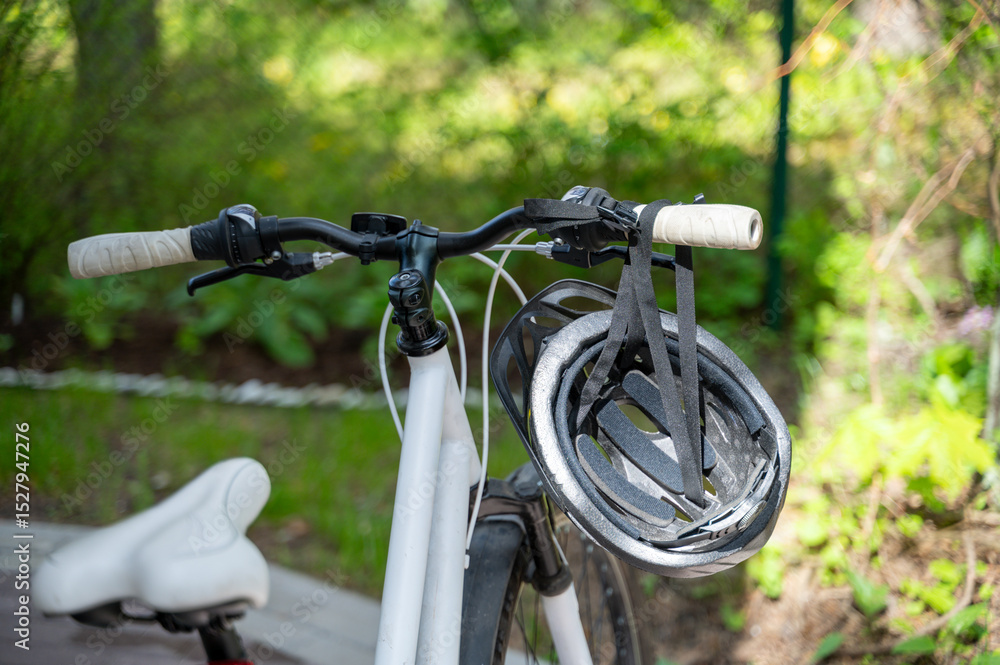 Fototapeta premium Close-up of handlebar and seat of bicycle, helmet hangs on handlebar. Safe and eco-friendly way of transportation