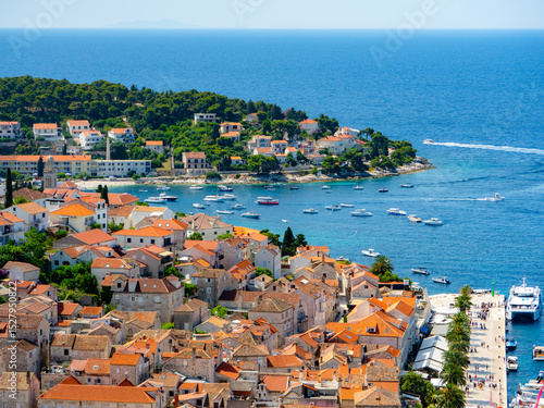 Aerial view of Hvar, Croatia—terracotta rooftops, lush hills, and a vibrant harbor on the Adriatic Sea, capturing the charm of Mediterranean island life and coastal beauty.