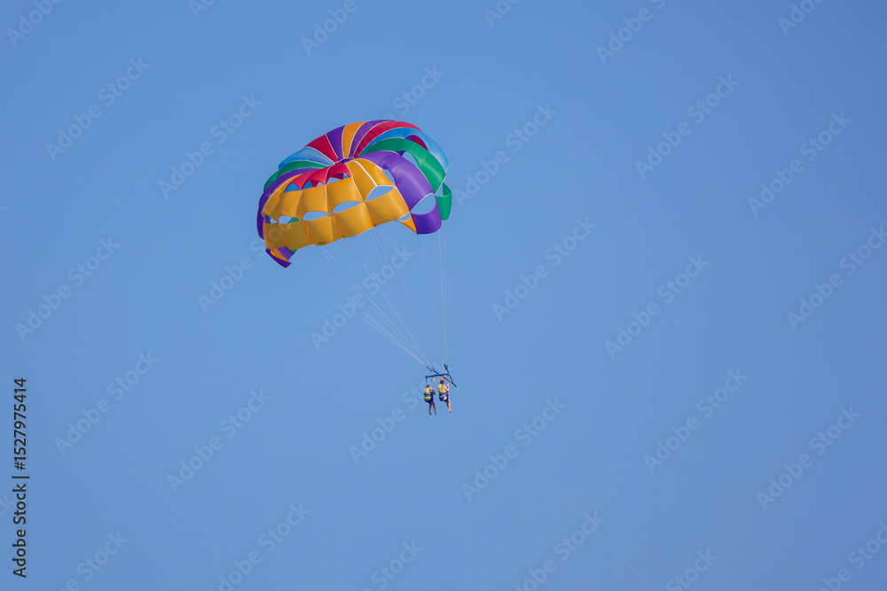 tourists parasailing on a sea seen against the clear blue sky tourists parasailing on a sea seen against the clear blue sky