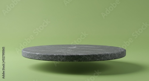A gray, mottled stone disc hovers in front of a muted green backdrop