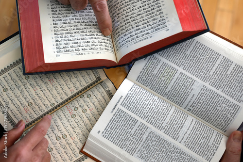 Three monotheistic religions. A Christian, a Jew, and a Muslim reading the Bible, the Torah, and the Quran. Symbol of peace and interfaith dialogue.