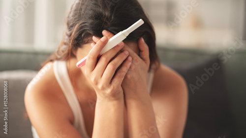 Young woman holding pregnancy test with negative result