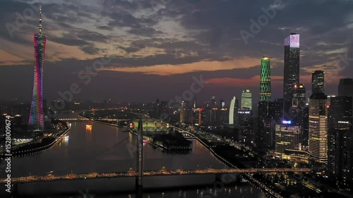 Evening traffic crosses guangzhou hunter bridge under a beautiful sunset sky with cantonese tower and illuminated city skyline