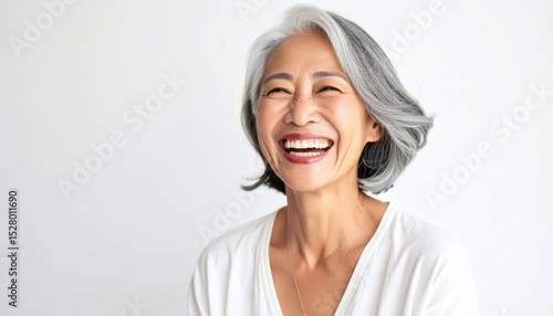 Joyful elderly woman with gray hair smiling happily against a white background, conveying warmth and positivity