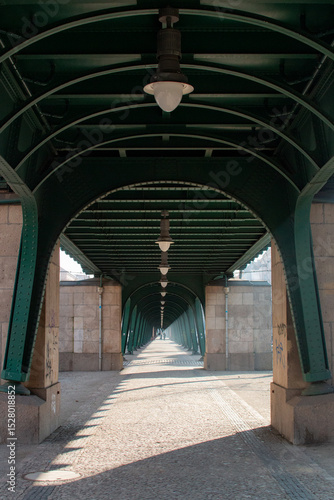 Photography Two People Walking Through the Arched Pedestrian Walkway of the Oberbaum Bridge
