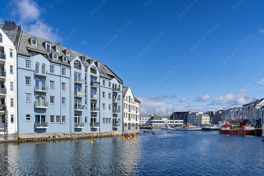 Naklejka premium Colorful Waterfront Houses with Recreational Activity Under Clear Blue Sky, Aalesund, Norway