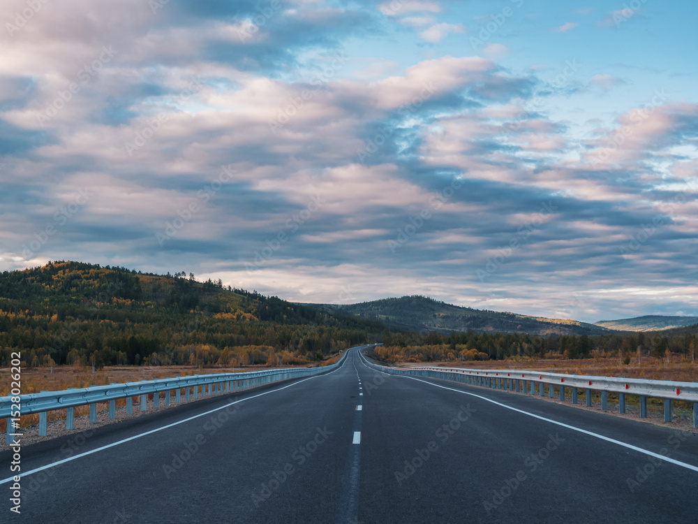 Fototapeta premium A long, open highway leads through a picturesque mountainous area.