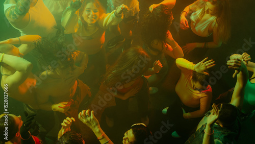 Fotografija Top view of people dancing energetically in colorful lighting