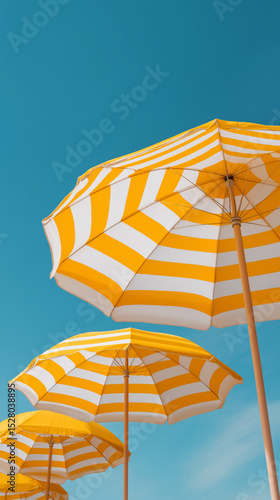 Yellow and white striped beach umbrellas standing tall against a clear blue sky