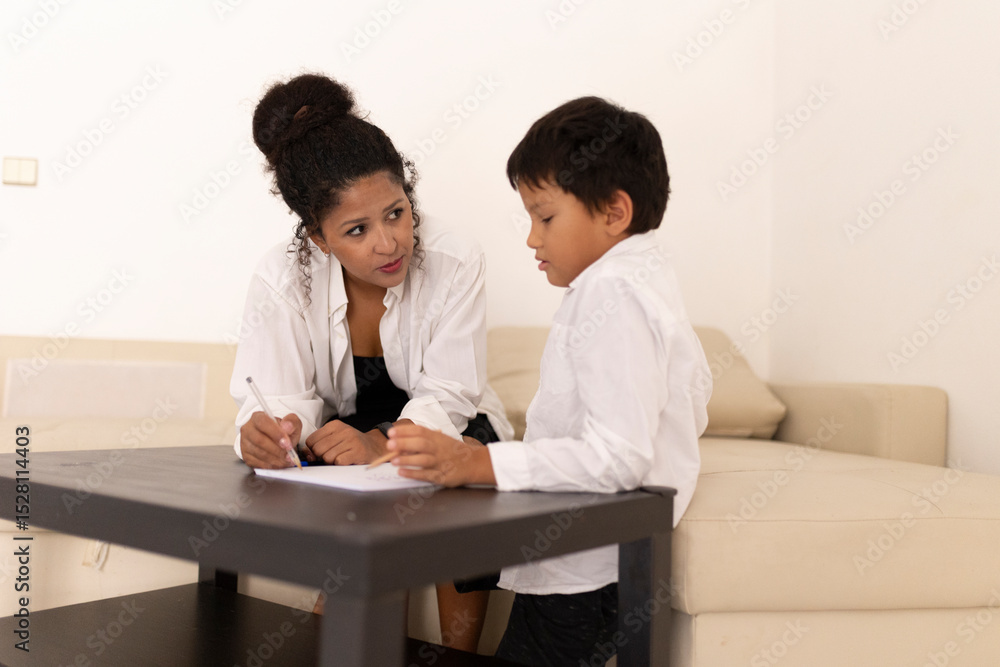Teacher helping young boy with homework in living room Teacher helping young boy with homework in living room