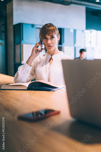 Wallpaper Mural Adult determined businesswoman making phone call near pleased coworker working on laptop in office Torontodigital.ca