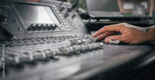 Obraz na plátně the hand of a tattooed person controlling a sound mixer at a live event