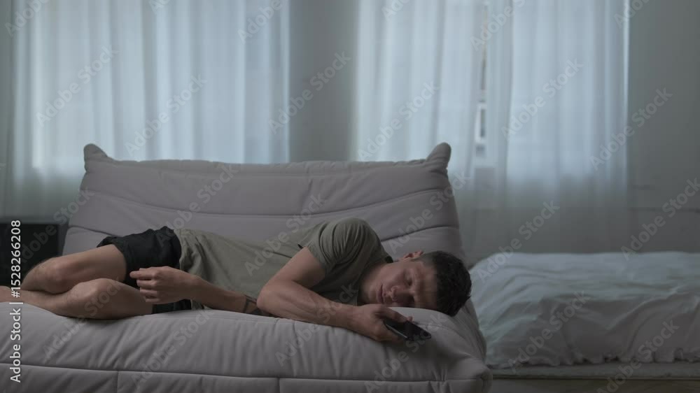 Exhausted man falls asleep holding his phone, drained by digital overload and constant screen time. Exhausted man falls asleep holding his phone, drained by digital overload and constant screen time.