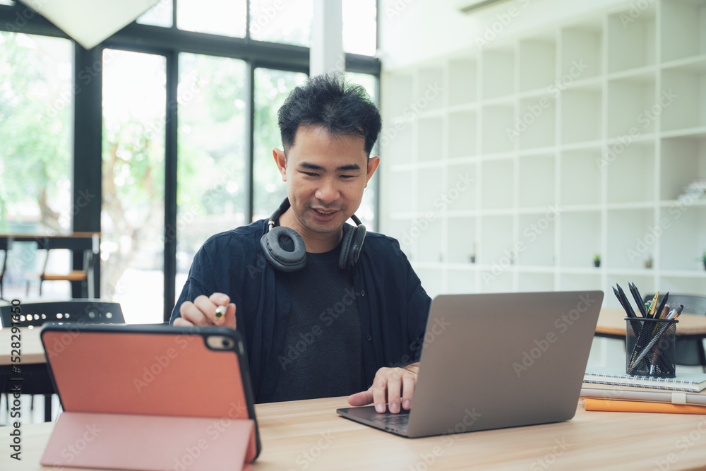 Fototapeta premium Man Working at Desk with Laptop and Tablet