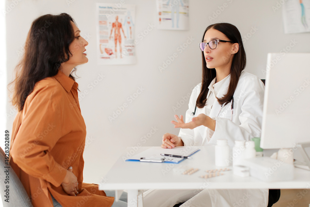 Medical specialist consulting middle aged female patient, complaining at abdominal pain due to pancreatitis, gastritis or diarrhea Medical specialist consulting middle aged female patient, complaining at abdominal pain due to pancreatitis, gastritis or diarrhea