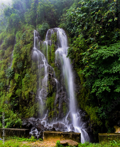 Multi-tiered waterfall amidst vibrant green foliage, with rushing water in Meghalaya. 