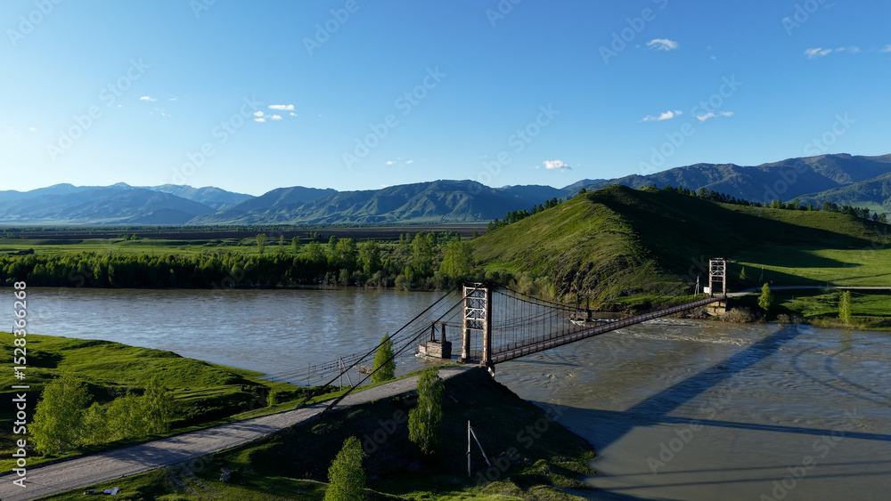 Fototapeta premium A bridge in the village of Multa in the Altai Mountains. A bridge across a cold mountain river in the mountains of the Altai Republic.