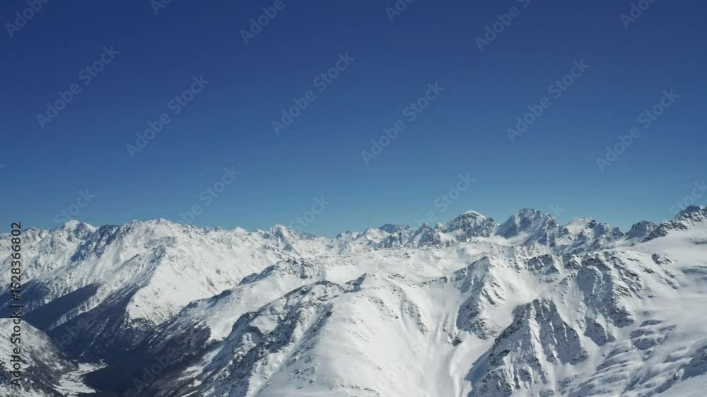 Snow-capped peaks of Mount Elbrus and Cheget in the Caucasus Mountains, a pristine winter panorama with glistening snow and deep blue sky under sunlight Snow-capped peaks of Mount Elbrus and Cheget in the Caucasus Mountains, a pristine winter panorama with glistening snow and deep blue sky under sunlight
