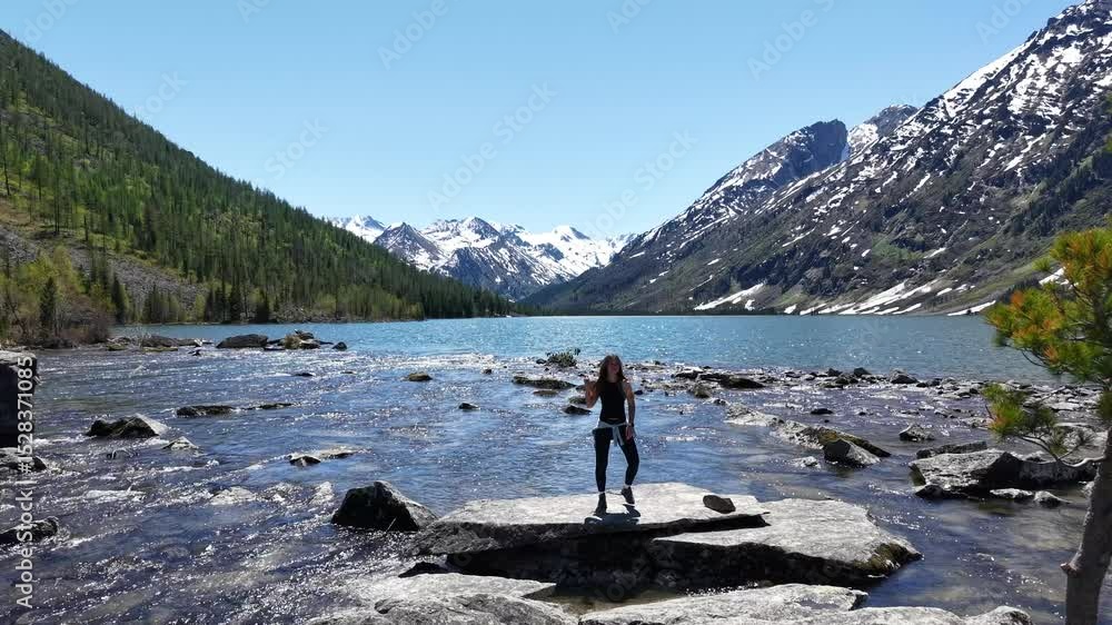 Woman hiker at mountain lake. Woman on the shore of Multinskoye Lake in Altai Mountains, hiking in the mountains Woman hiker at mountain lake. Woman on the shore of Multinskoye Lake in Altai Mountains, hiking in the mountains