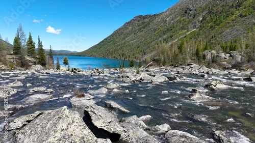Cinematic views of a mountain lake with high mountains. Multinsky lakes are high-mountain lakes in the Altai Mountains. Rapids of water between two lakes, drone flight over running water.
