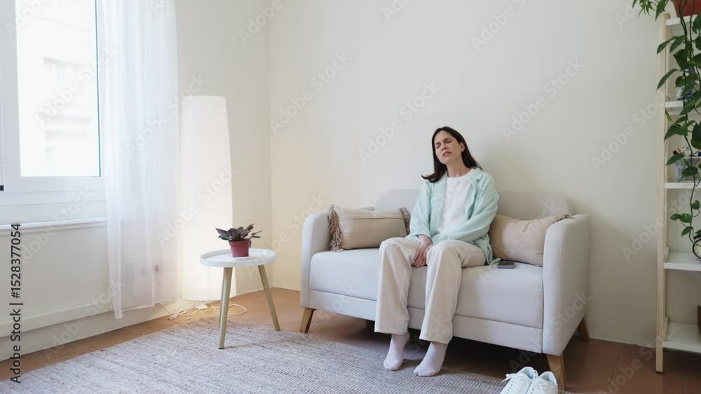 Young woman putting down smartphone and relaxing on sofa Young woman putting down smartphone and relaxing on sofa
