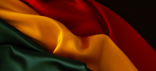 Black History Month, Juneteenth background. Red, yellow, green colors satin silk flag draperies. Top view