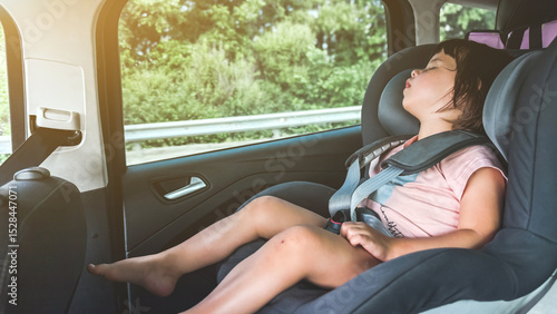 Fotografie A young child girl 2-3 years sleeping peacefully in a car seat during a car ride