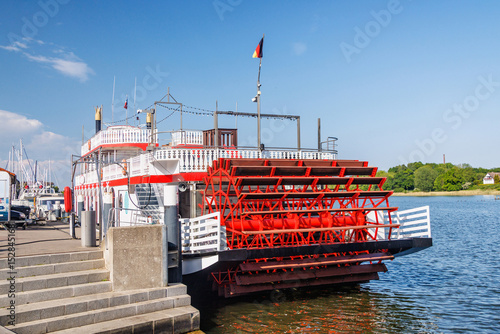 Paddle steamer docked at pier with german flag flying high in Kappeln