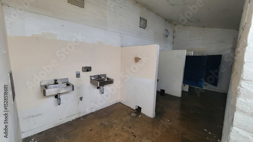 Fotografie Lacking proper care public restroom facility with wet floors, stainless hand sin